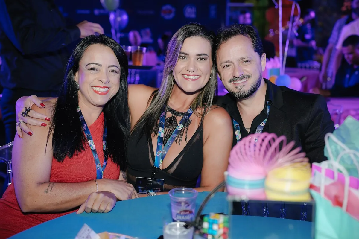 Três empresários sorrindo à mesa durante o MOVE Anos 2000